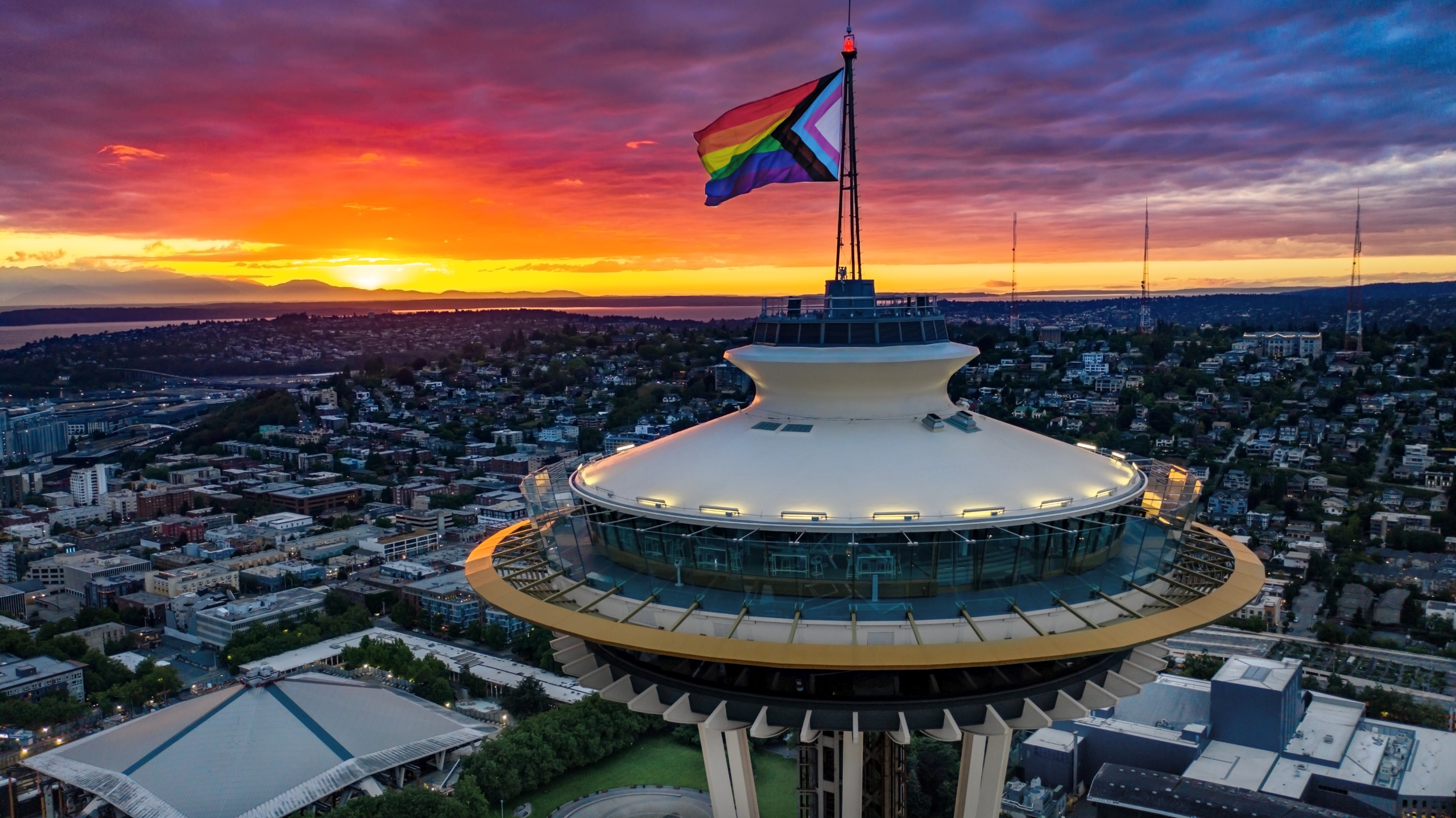 Photo of the Progress Pride Flag flying atop the Seattle Space Needle - photo by Kevin Henry - Atomic Aerials